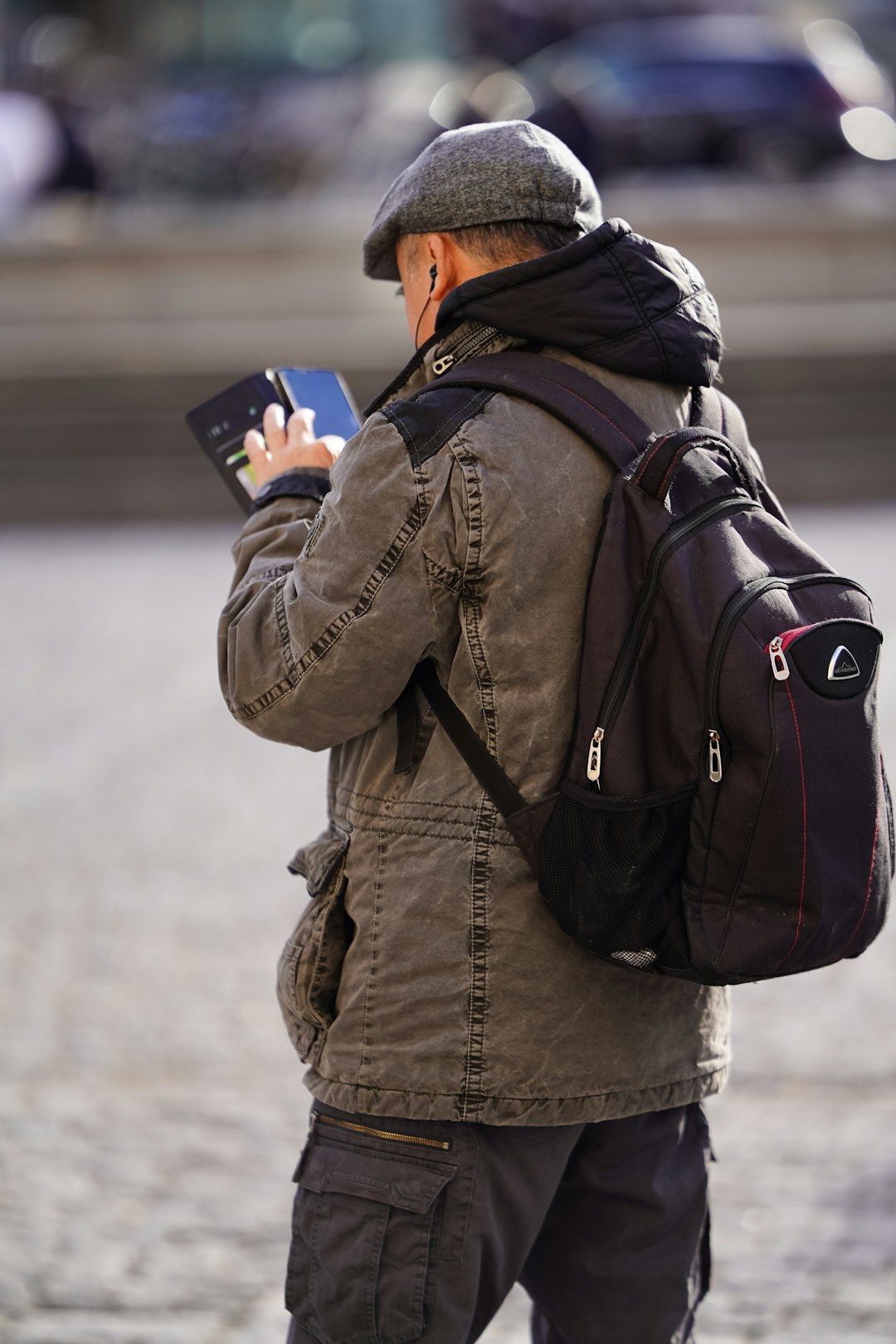 A man with a backpack looking at his cell phone