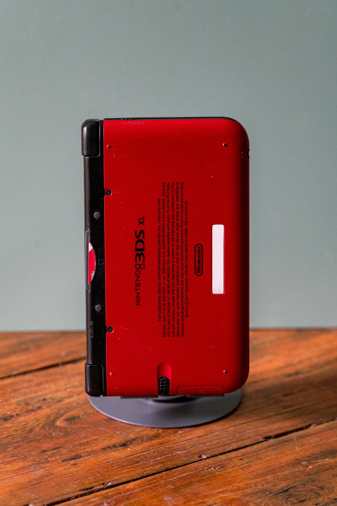 A red nintendo 3ds is on its charging dock.
